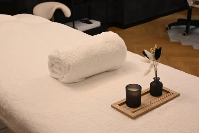 Head massage benefits — calming spa massage table with candle and rolled towel